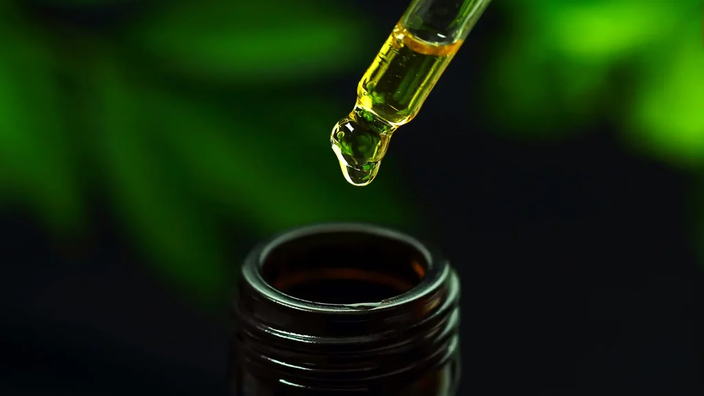 Flacon d’huile de CBD avec pipette sur fond vert flouté